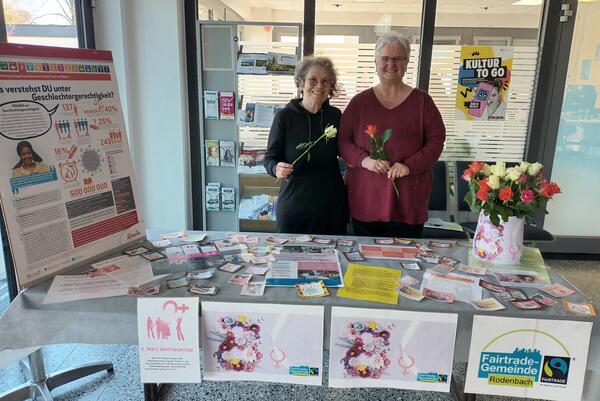 Astrid Rie&szlig;-Wenzel, Mitglied der Rodenbacher Fairtrade-Steuerungsgruppe, und Birgit Peck, Mitarbeiterin im Rodenbacher Rathaus, am Informationsstand zum Weltfrauentag 2025 mit fairen Rosen.